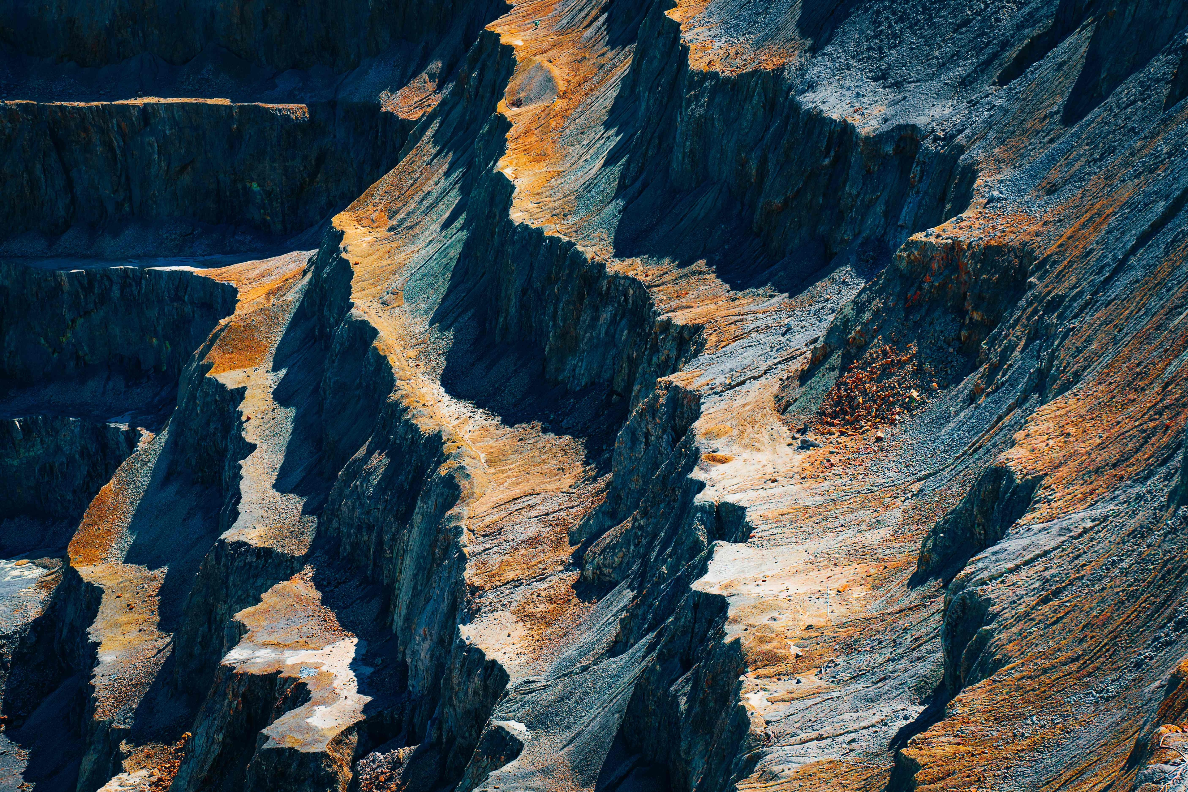 Dramatic aerial view of quarry with deep blue rock faces and golden highlights