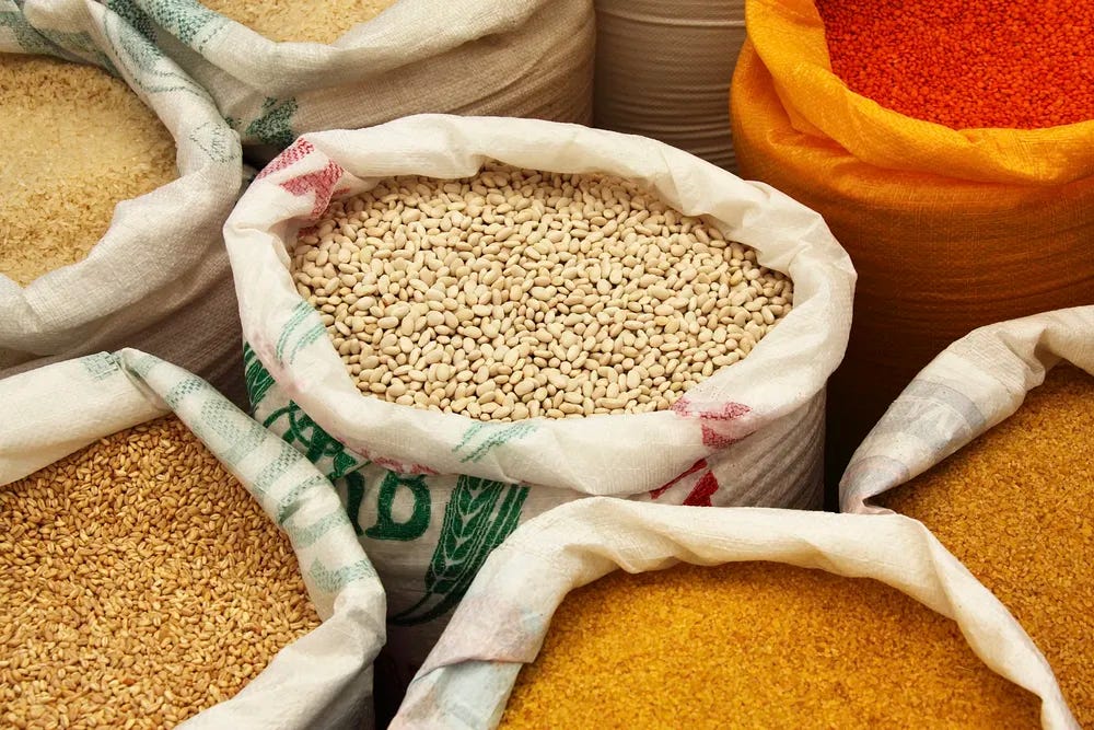 Various commodity sacks filled with grains, beans, and spices in a market setting